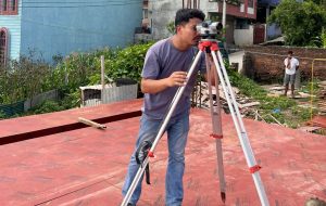 An ST Builders engineer performing a professional site survey with a leveling instrument in Nepal, ensuring precise planning for a new construction project.