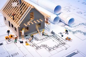 Miniature construction workers building a model house on top of architectural blueprints, representing services of construction companies in Nepal.